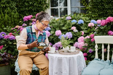 Foto de Hermosa mujer madura alegre beber té caliente en el desayuno en el jardín de su casa en Inglaterra - Imagen libre de derechos