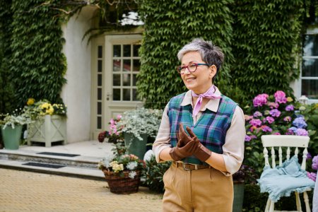 Téléchargez les photos : Sophistiqué mature femme joyeuse en tenue élégante posant près de sa maison en Angleterre et regardant loin - en image libre de droit