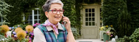elegant cheerful mature woman with glasses talking by phone net to her house in England, banner