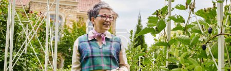 chic merry mature woman with short hair in elegant vivid attire taking care of her plants, banner