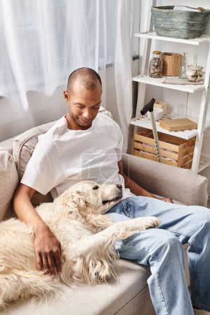 Un homme atteint de myasthénie grave se relaxant sur un canapé avec son chien du Labrador, mettant en valeur la diversité et l'inclusion.