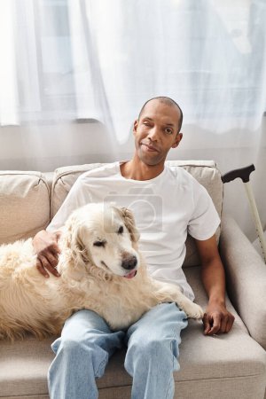 Ein afroamerikanischer Mann mit Myasthenia gravis entspannt sich zu Hause auf einer Couch mit seinem treuen Labrador-Hund an seiner Seite.