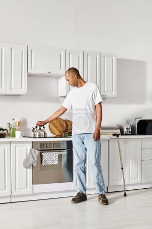 Ein afroamerikanischer Mann mit Myasthenia gravis steht in einer Küche und schaut nachdenklich neben einer Spüle.