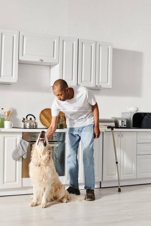 An African American man with myasthenia gravis stands in a kitchen, sharing a harmonious moment with his Labrador dog.