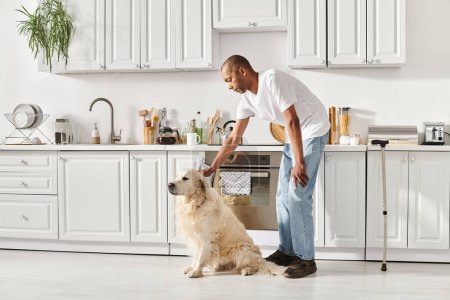 A disabled African American man with myasthenia gravis petting his Labrador dog in a warm kitchen.