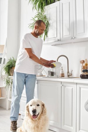 Ein Afroamerikaner steht in einer Küche neben seinem Labrador-Hund.