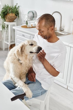 Un hombre afroamericano discapacitado acaricia amorosamente a su leal Labrador en un acogedor entorno de cocina, irradiando calidez y compañía..
