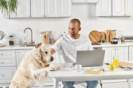 Ein behinderter Afroamerikaner sitzt an einem Tisch mit Laptop, begleitet von einem treuen Labrador-Hund.