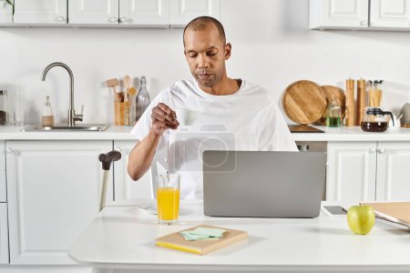 Photo for A diverse African American man with myasthenia gravis stands confidently in front of a laptop computer. - Royalty Free Image