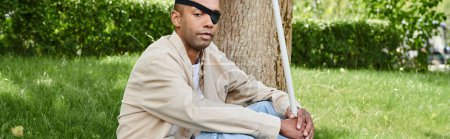 An African American man with myasthenia gravis syndrome sits beside a tree