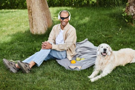 Ein Mann mit Myasthenia-gravis-Syndrom sitzt gedankenverloren auf einer Decke neben seinem treuen Labrador-Hund.