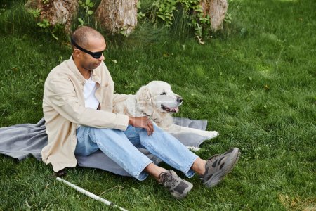 A disabled African American man with myasthenia gravis syndrome sits in the grass with his loyal Labrador dog.