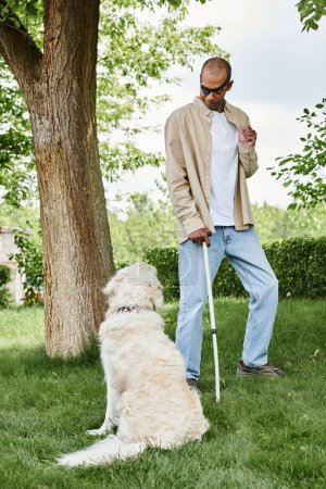 A disabled African American man with myasthenia gravis syndrome standing next to a Labrador dog on a vibrant green field.