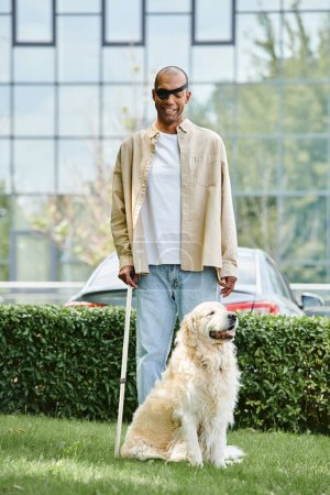 Un hombre afroamericano discapacitado de pie junto a un perro labrador en un campo verde exuberante, que simboliza la armonía y la inclusividad.