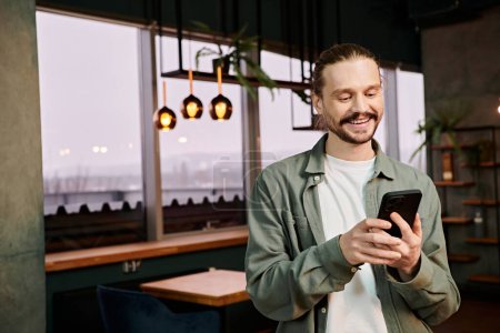 Téléchargez les photos : Homme parcourt son téléphone portable tout en se tenant dans un restaurant moderne - en image libre de droit