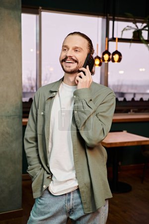 Foto de Un hombre de pie en un restaurante de moda, comprometido en una animada conversación telefónica. - Imagen libre de derechos