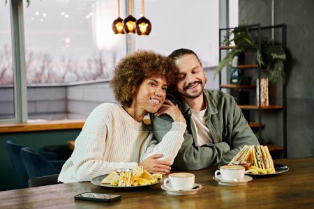An African American woman and a man enjoy a meal together at a table in a modern cafe, surrounded by delicious food.
