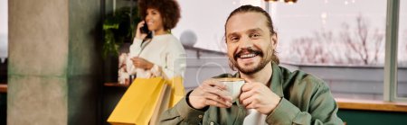 Téléchargez les photos : Un homme assis à une table, dégustant une tasse de café dans un café moderne. - en image libre de droit