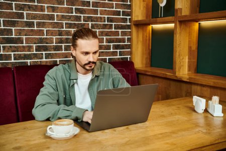 A man working on a laptop computer at a table in a modern cafe.