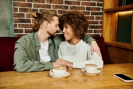 Ein Mann und eine Frau, beide Afroamerikaner, sitzen an einem Cafétisch und genießen gemeinsam Tassen Kaffee.