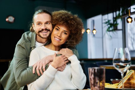 An African American woman and man share a tender hug in a modern cafe setting.