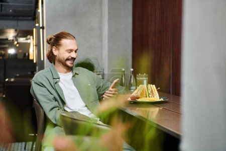 Ein Mann sitzt an einem Tisch und genießt einen Teller mit Essen in einem modernen Café-Ambiente.