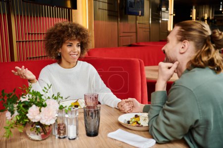 couple engage in animated conversation at a table in a modern cafe.