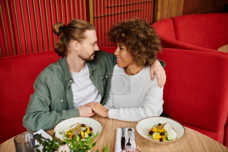 Un hombre y una mujer disfrutan de una comida juntos en una mesa en una cafetería moderna.