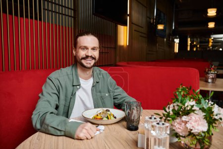 Foto de Un hombre sentado en una mesa con un plato de comida frente a él. - Imagen libre de derechos