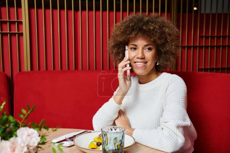 An African American woman enjoying a delicious meal at a table in a modern cafe.