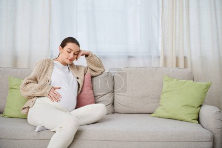 A beautiful pregnant woman sits comfortably on a couch in a cozy living room, surrounded by warmth and anticipation.