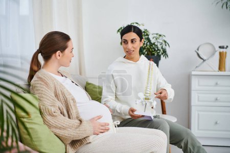 Una mujer embarazada sentada en un sofá junto a su entrenador durante los cursos de padres.