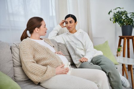 Una mujer embarazada y su entrenador se sientan juntos en un sofá acogedor durante los cursos de los padres, construyendo un fuerte vínculo.
