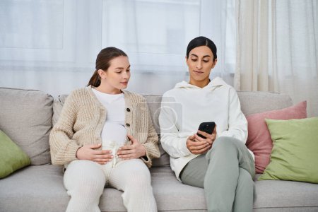 Eine schwangere Frau und ihr Trainer sitzen während des Elternkurses bequem auf einer Couch.