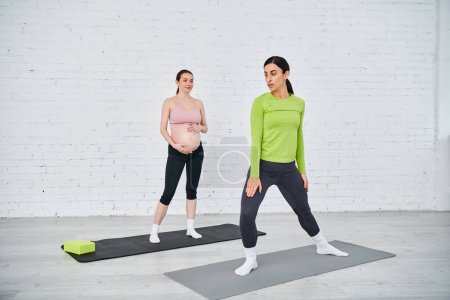 Two pregnant women stand confidently on yoga mats, practicing exercises guided by their coach during parents courses.