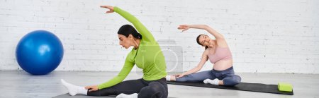 Foto de Una mujer embarazada practica yoga con su entrenador durante los cursos de padres, ambos sentados en colchonetas de yoga en un entorno tranquilo. - Imagen libre de derechos