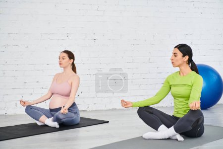 Zwei Frauen sitzen auf Yogamatten und führen eine friedliche Sitzung durch.