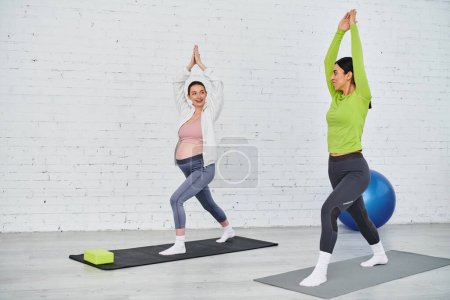 Una mujer embarazada practica yoga con su instructor sobre esterillas de yoga en un entorno sereno.