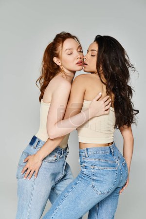 Foto de Dos mujeres en jeans compartiendo un abrazo alegre. - Imagen libre de derechos