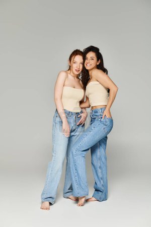 Foto de Two women in jeans, a loving lesbian couple, standing together happily. - Imagen libre de derechos