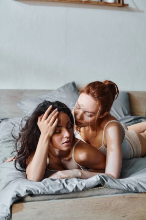 Foto de Dos mujeres sofisticadas en traje elegante que yacen serenamente en una cama juntas. - Imagen libre de derechos
