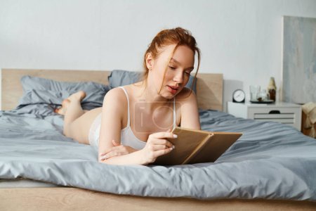 Une femme en tenue élégante lisant paisiblement un livre sur un lit.