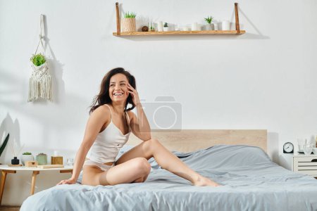 Téléchargez les photos : Femme en tenue élégante s'assoit sur le lit. - en image libre de droit