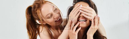Photo for Two laughing women in elegant attire covering their faces in delight. - Royalty Free Image