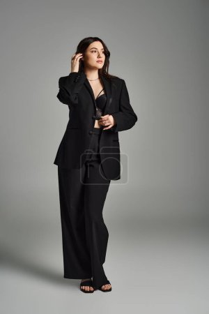 A stylish plus-size woman in a black suit conversing on a cell phone, exuding confidence and sophistication.