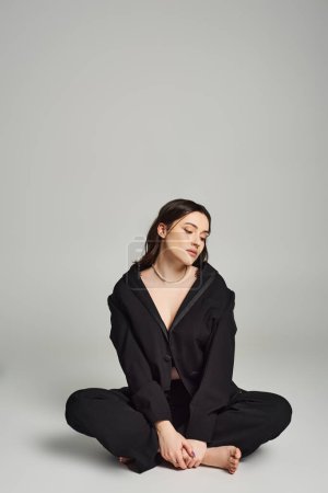 Eine schöne Plus-Size-Frau in stylischer Kleidung sitzt mit geschlossenen Augen auf dem Boden und strahlt Ruhe und Introspektion aus.