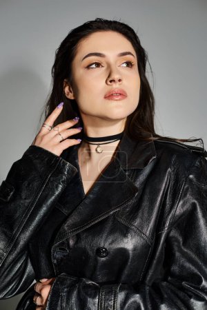 Stunning plus-size woman in a black leather jacket and choker posing against a gray backdrop.
