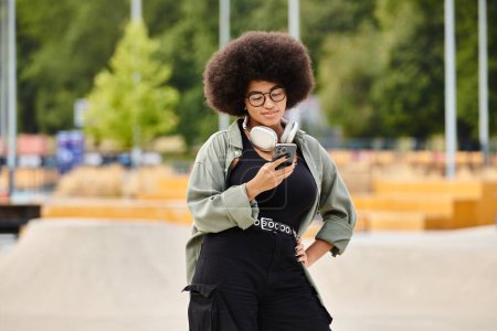 Eine stylische Frau mit voluminöser Afro-Frisur hält ein Handy in der Hand.