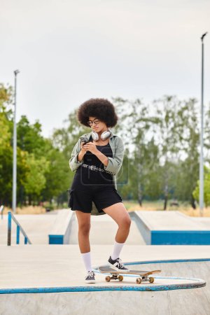 Photo for An African American teenager with curly hair confidently standing with a skateboard in a skate park. - Royalty Free Image