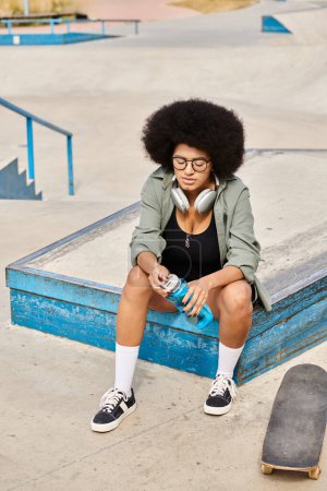 Une jeune afro-américaine aux cheveux bouclés est assise sur une boîte bleue à côté d'une planche à roulettes dans un skate park urbain.